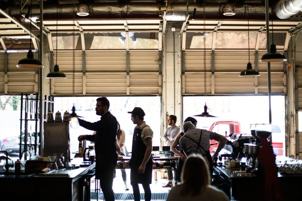 Una cafetería llena a la hora del desayuno, con el equipo detrás de la barra
